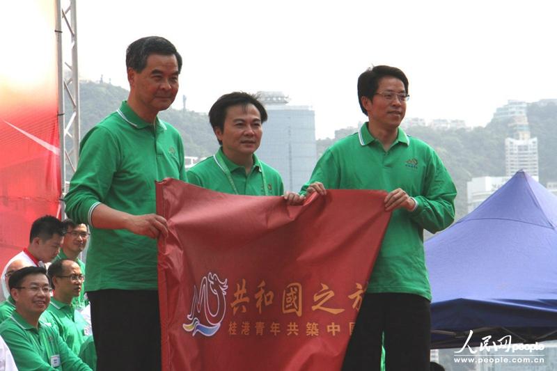 特区行政长官梁振英、中联办主任张晓明为专列团团长马鸿铭颁授团旗。（摄影：郭晓桐）