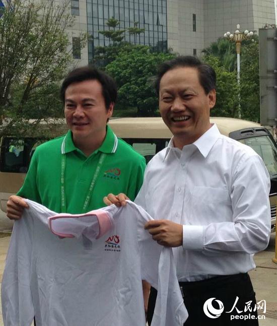 “共和国之旅广西专列团”团长马鸿铭向彭清华(右)赠送专列团纪念衫。（摄影：曹海扬）